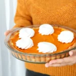 Classic Libby’s pumpkin pie topped with whipped cream on a wooden table during the holiday season