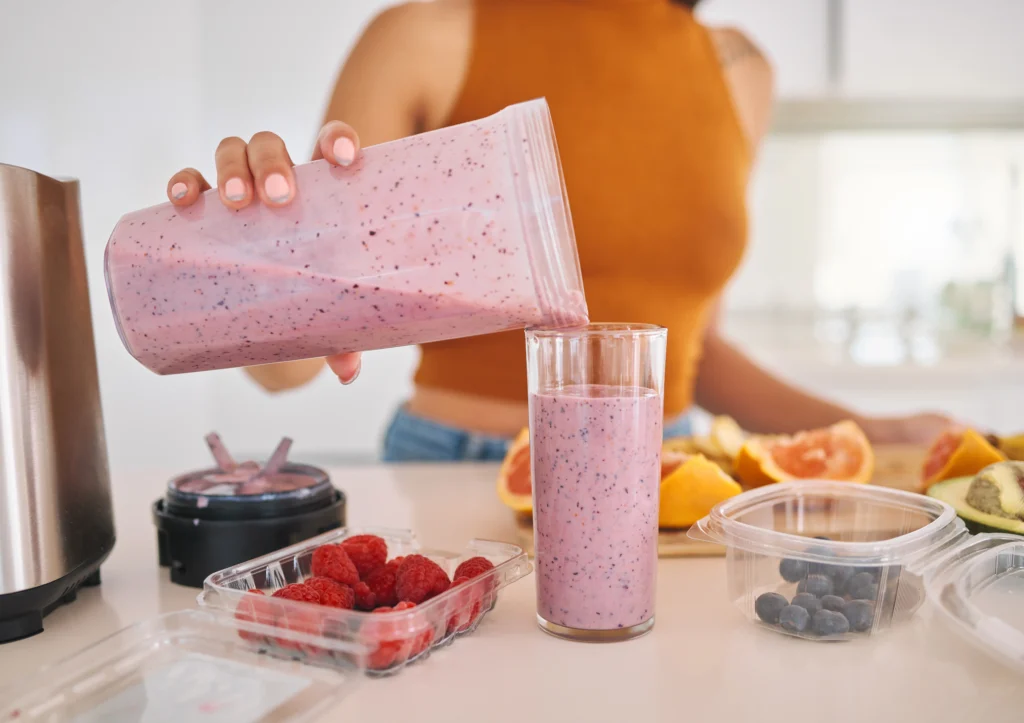 Glass of healthy protein shake made with banana, milk, and peanut butter on a kitchen counter
