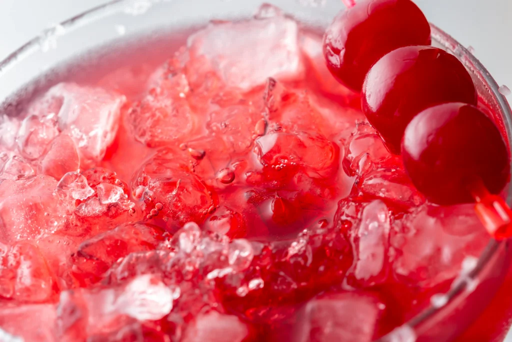 A refreshing glass of Shirley Temple made with just three ingredients, garnished with bright red maraschino cherries and served over ice for a classic, family-friendly mocktail.