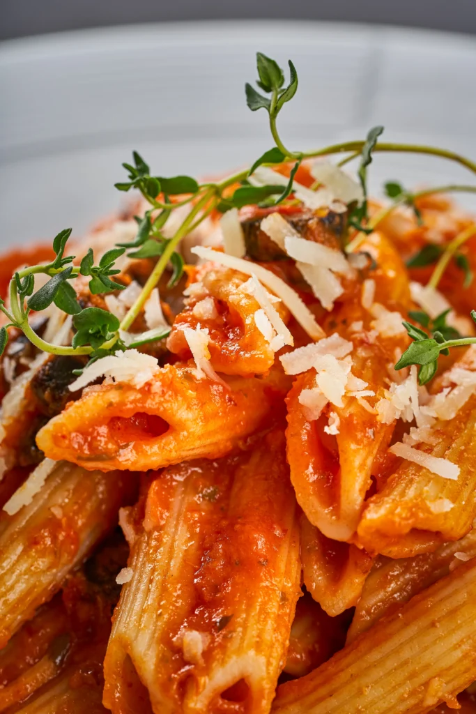 Creamy Penne alla Vodka pasta served in a bowl with rich tomato cream sauce, Parmesan cheese, and fresh basil garnish.