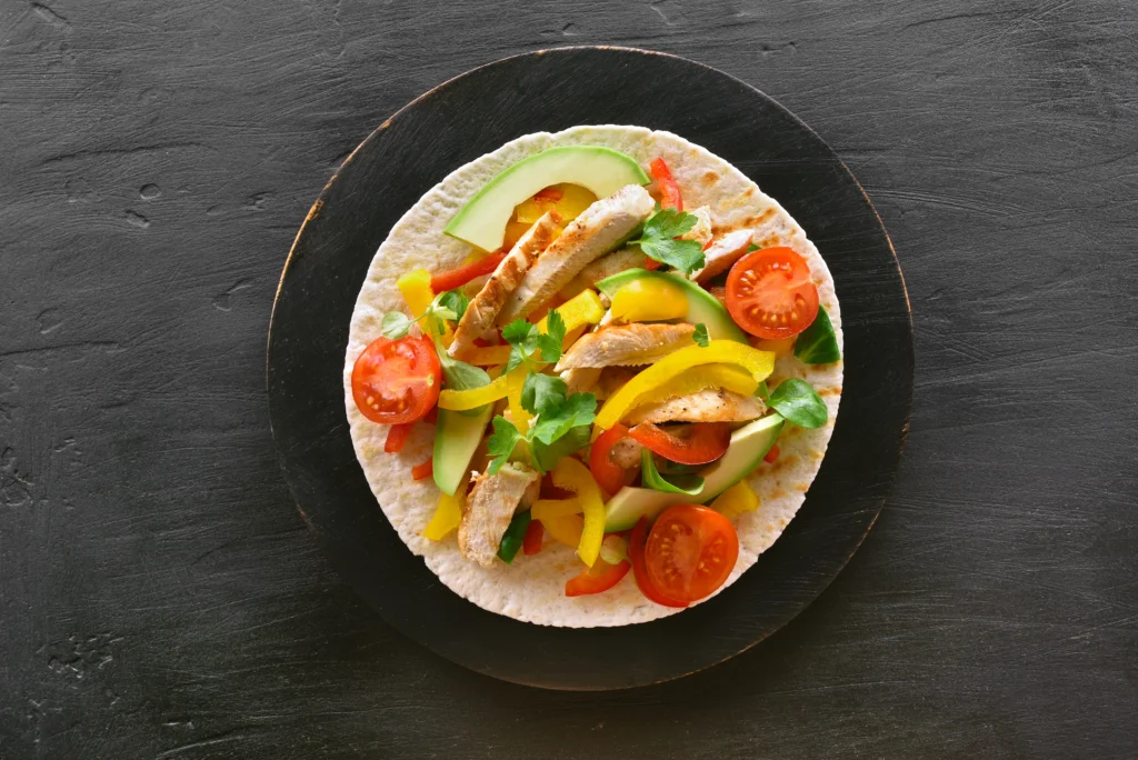 Sheet pan chicken fajitas with seasoned grilled chicken strips, colorful bell peppers, and onions roasted to perfection, served with warm tortillas and fresh lime wedges.