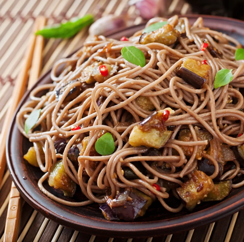 Bowl of cold soba noodle salad with fresh vegetables, edamame, and sesame dressing, served as a light and refreshing summer lunch.