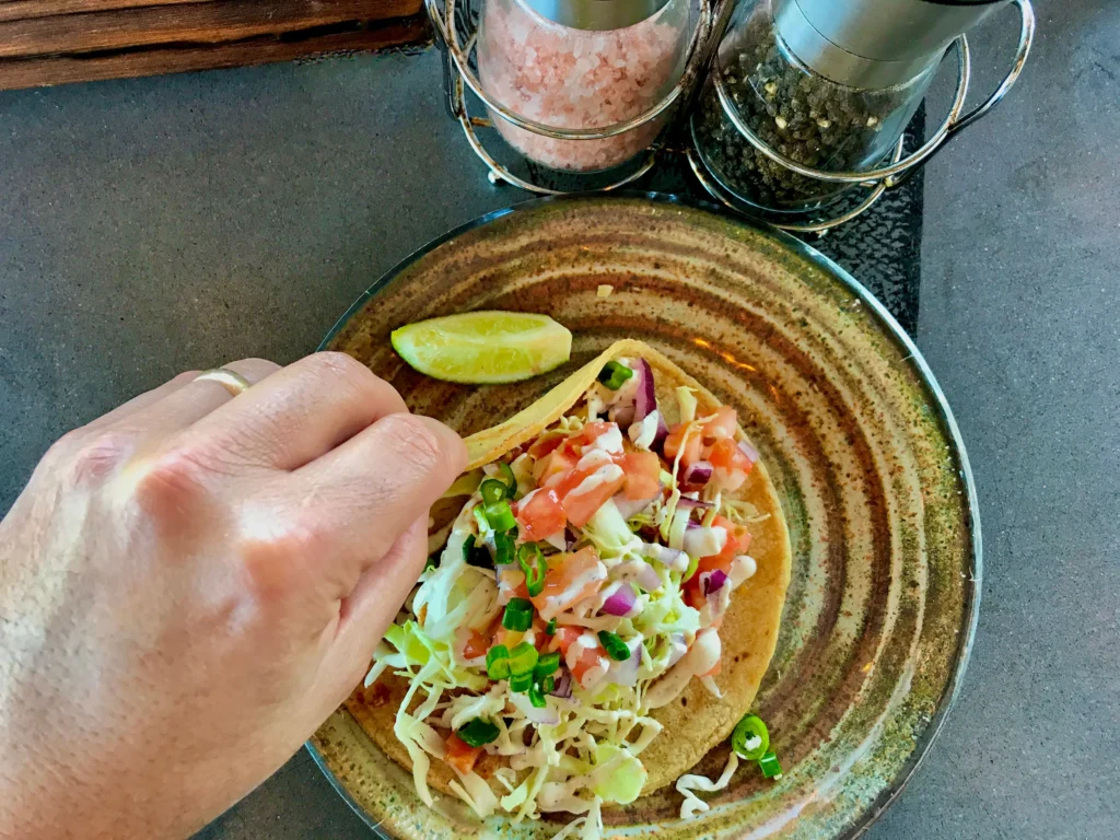 A close-up of restaurant-style smash burger tacos filled with crispy smashed beef patties, melted cheese, fresh lettuce, pickles, diced onions, and creamy burger sauce on toasted tortillas.