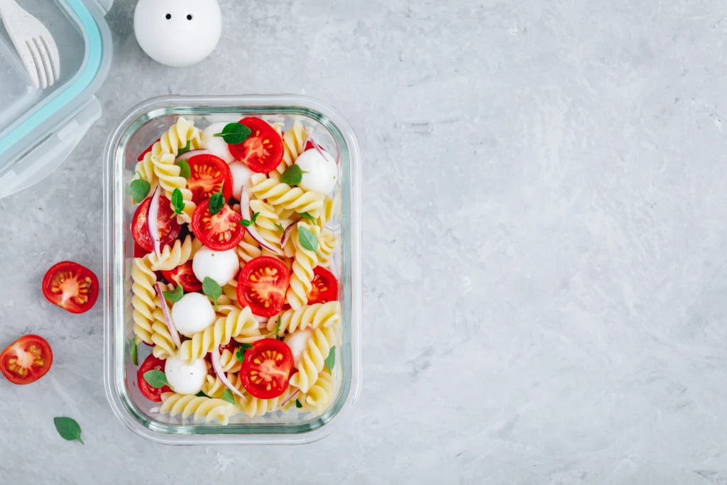 Fresh Tomato & Feta Pasta Salad made with rotini pasta, cherry tomatoes, crumbled feta cheese, cucumber, basil, and a lemon olive oil dressing in a serving bowl.
