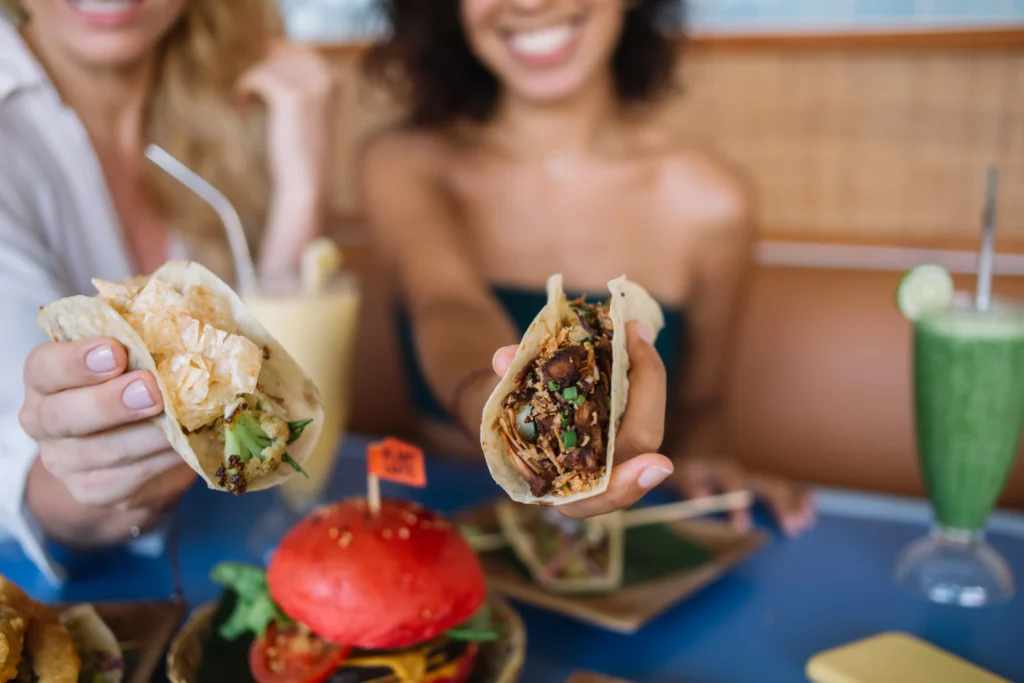 A close-up of restaurant-style smash burger tacos filled with crispy smashed beef patties, melted cheese, fresh lettuce, pickles, diced onions, and creamy burger sauce on toasted tortillas.