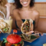A close-up of restaurant-style smash burger tacos filled with crispy smashed beef patties, melted cheese, fresh lettuce, pickles, diced onions, and creamy burger sauce on toasted tortillas.