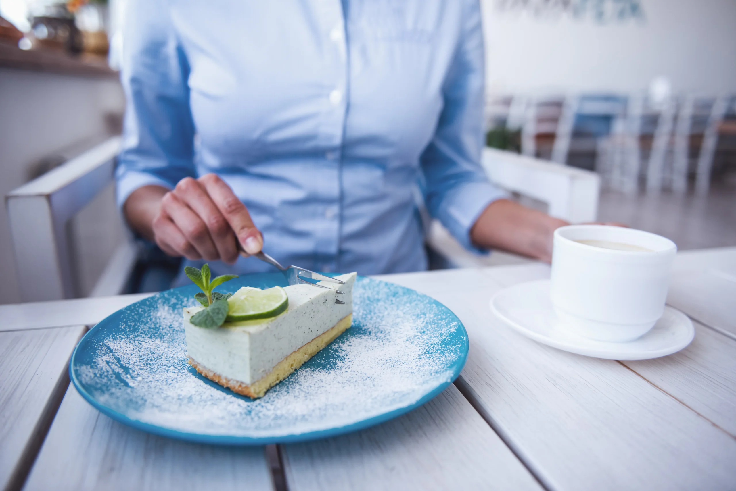 Slice of creamy lime icebox pie topped with whipped cream and fresh lime zest on a graham cracker crust, served on a white dessert plate.