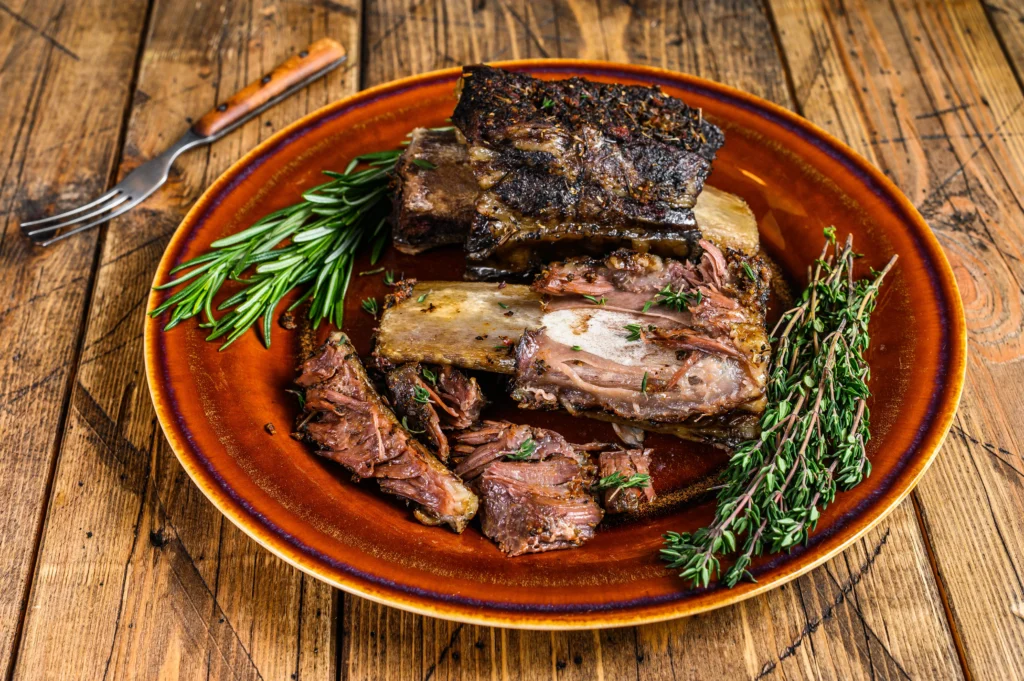 Fall-Off-The-Bone Braised Short Ribs served with rich sauce and vegetables on a rustic plate
