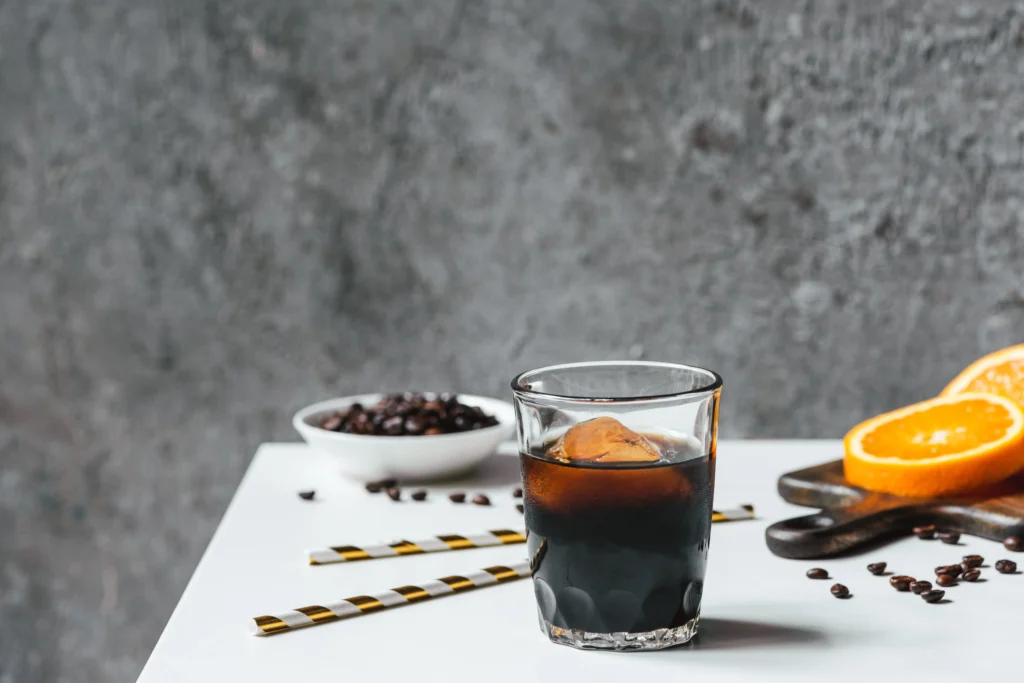 Carajillo recipe with espresso and Licor 43 served in a glass with coffee beans and cinnamon sticks
