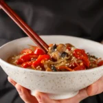 Bowl of cold soba noodle salad with fresh vegetables, edamame, and sesame dressing, served as a light and refreshing summer lunch.