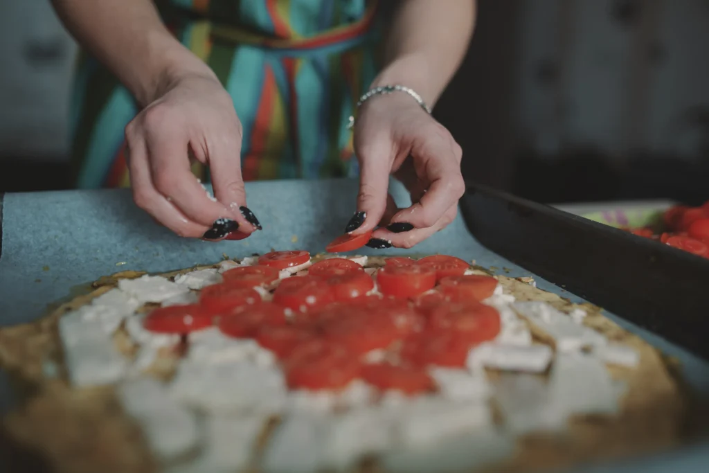 Freshly baked cottage cheese flatbread pizza topped with melted mozzarella, cherry tomatoes, basil leaves, and herbs, served on a wooden board for a healthy high-protein meal.