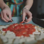 Freshly baked cottage cheese flatbread pizza topped with melted mozzarella, cherry tomatoes, basil leaves, and herbs, served on a wooden board for a healthy high-protein meal.