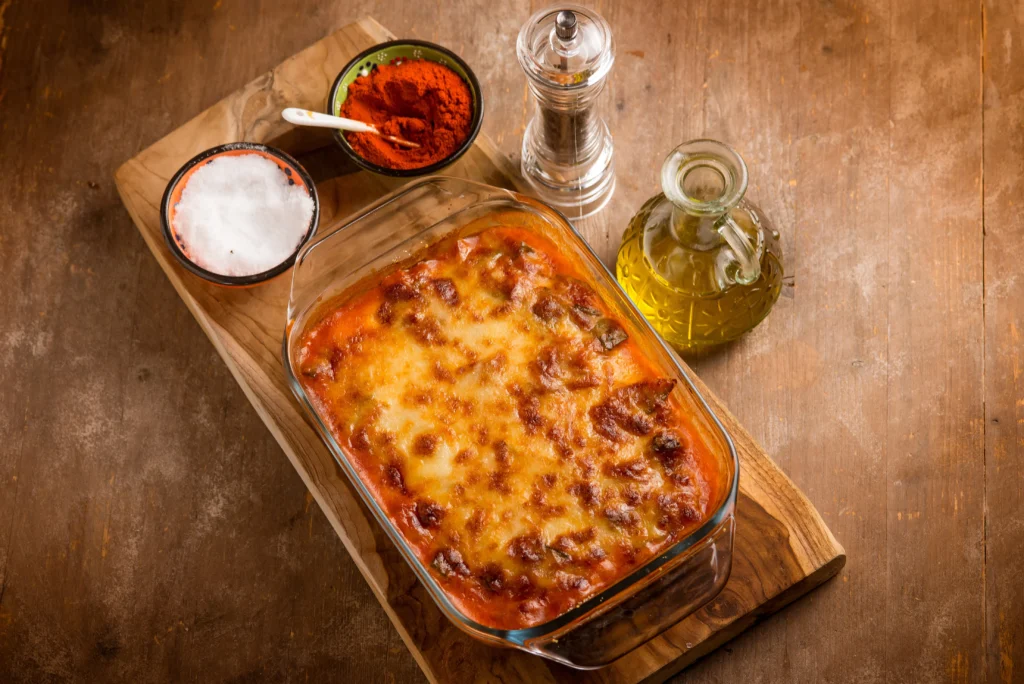 A hearty bowl of lasagna beans topped with melted mozzarella, grated Parmesan, fresh basil, and rich tomato sauce, served with crusty bread.