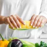 A vibrant bowl of authentic Mexican Street Corn Salad (Elote Salad) made with grilled sweet corn, cotija cheese, cilantro, lime wedges, and chili powder, served fresh in a rustic bowl.