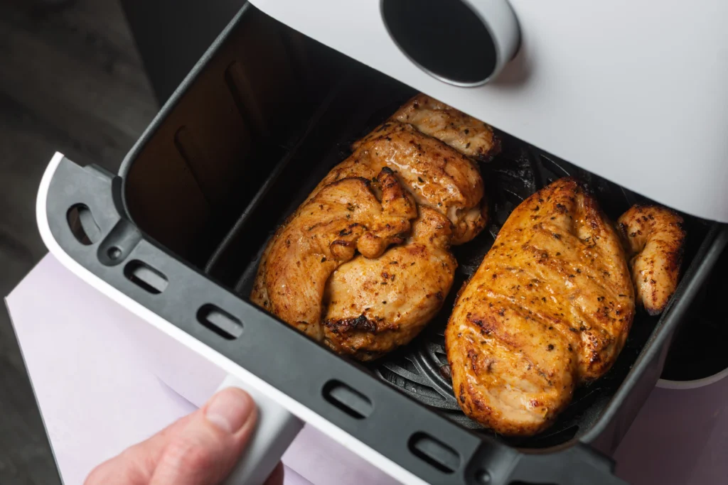 Juicy air fryer chicken breast served on a plate with roasted vegetables and fresh herbs, perfectly seasoned and cooked until golden brown.