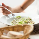 Creamy lemony risotto served with fresh Parmesan cheese, lemon zest, herbs, and cracked black pepper in a rustic white bowl.
