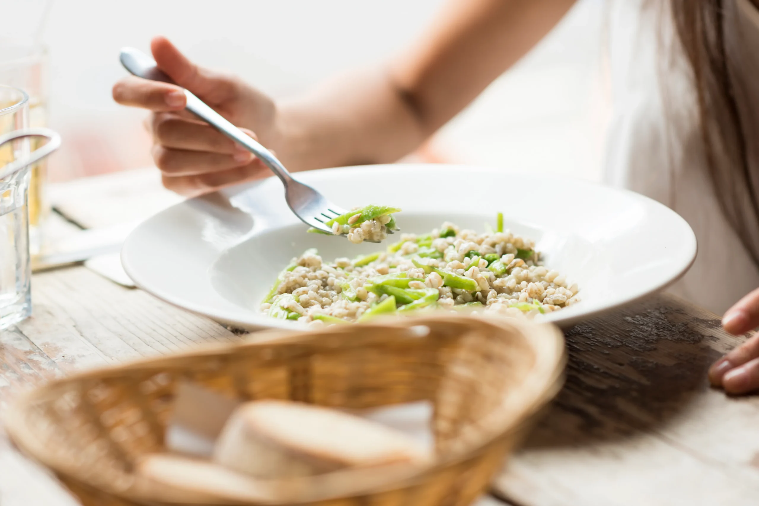 Creamy lemony risotto served with fresh Parmesan cheese, lemon zest, herbs, and cracked black pepper in a rustic white bowl.