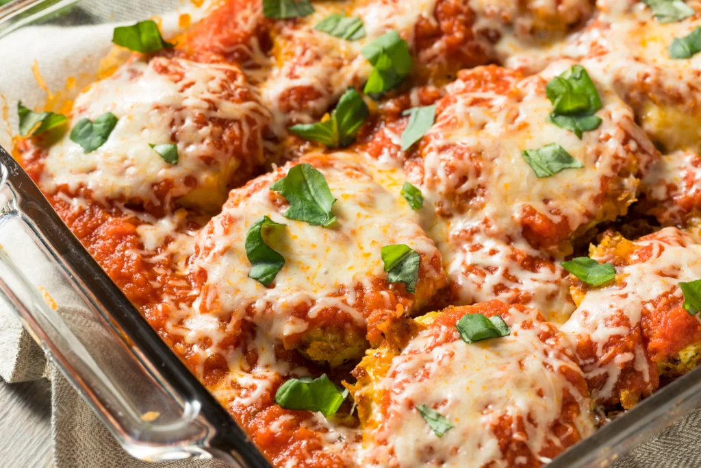 Crispy ground chicken Parmesan patties served with fresh parsley, grated Parmesan cheese, and marinara sauce on a white plate.