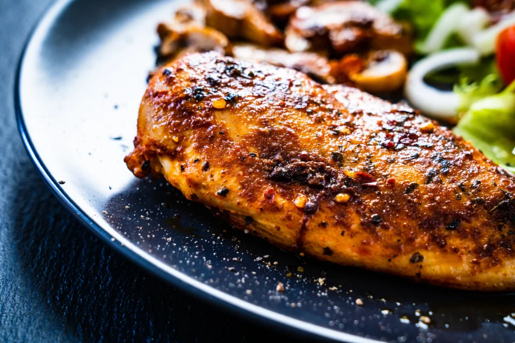Juicy air fryer chicken breast served on a plate with roasted vegetables and fresh herbs, perfectly seasoned and cooked until golden brown.