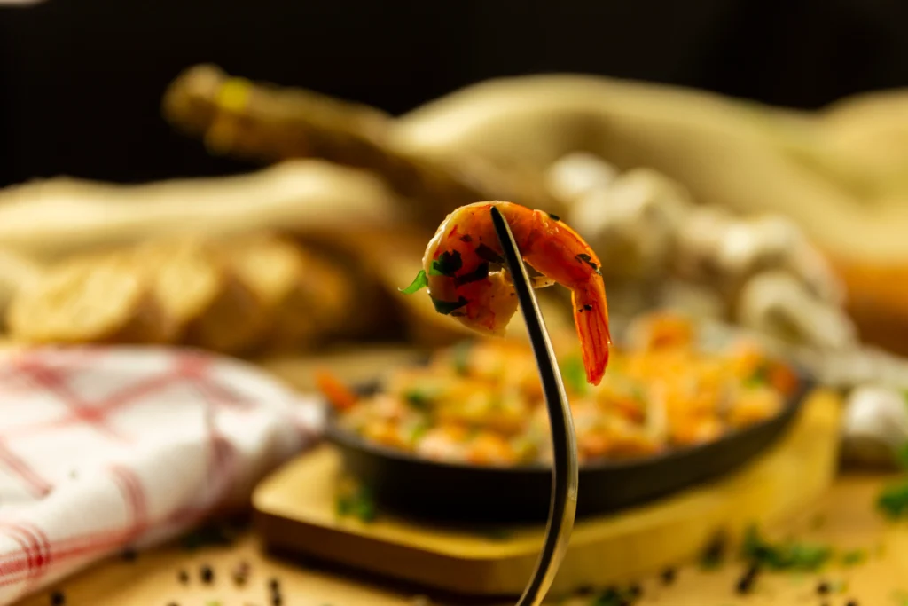 Smoky shrimp with sliced chorizo cooked in a rich paprika-infused sauce, garnished with fresh parsley and served in a rustic skillet with lemon wedges.