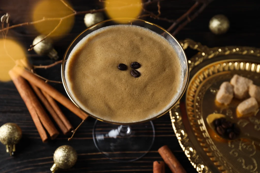 Classic Espresso Martini served in a chilled martini glass with a creamy foam topping and three coffee beans, set beside fresh espresso and coffee beans on a dark bar surface.