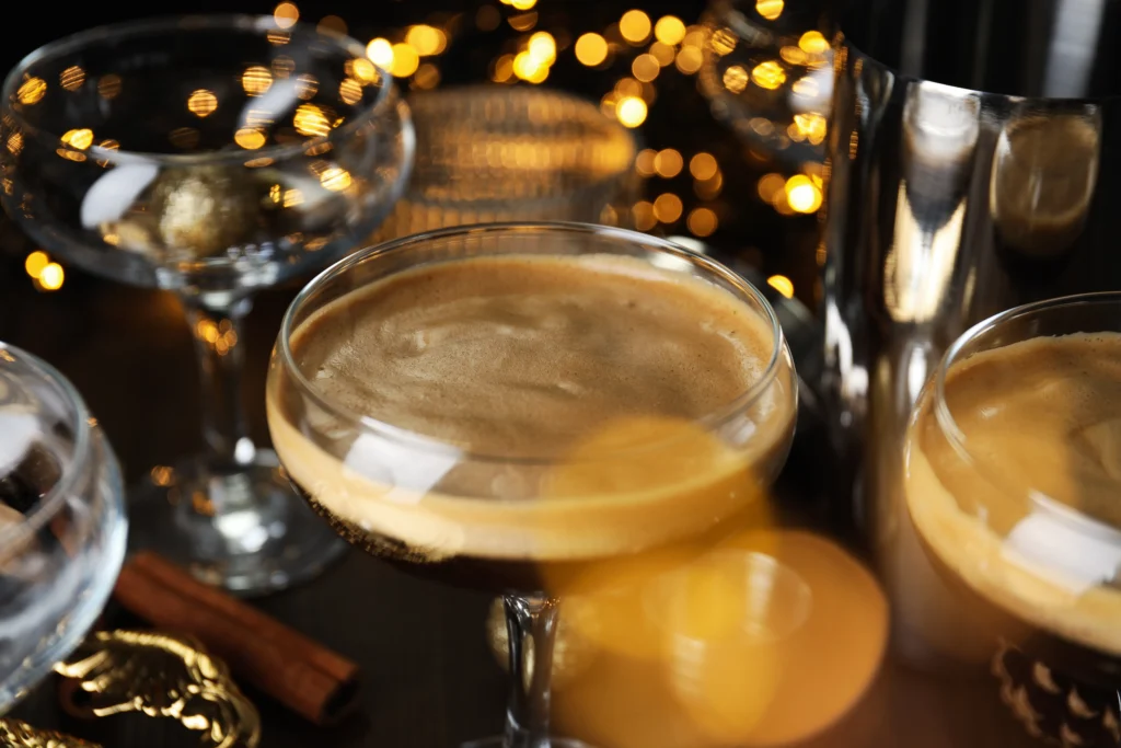 Classic Espresso Martini served in a chilled martini glass with a creamy foam topping and three coffee beans, set beside fresh espresso and coffee beans on a dark bar surface.