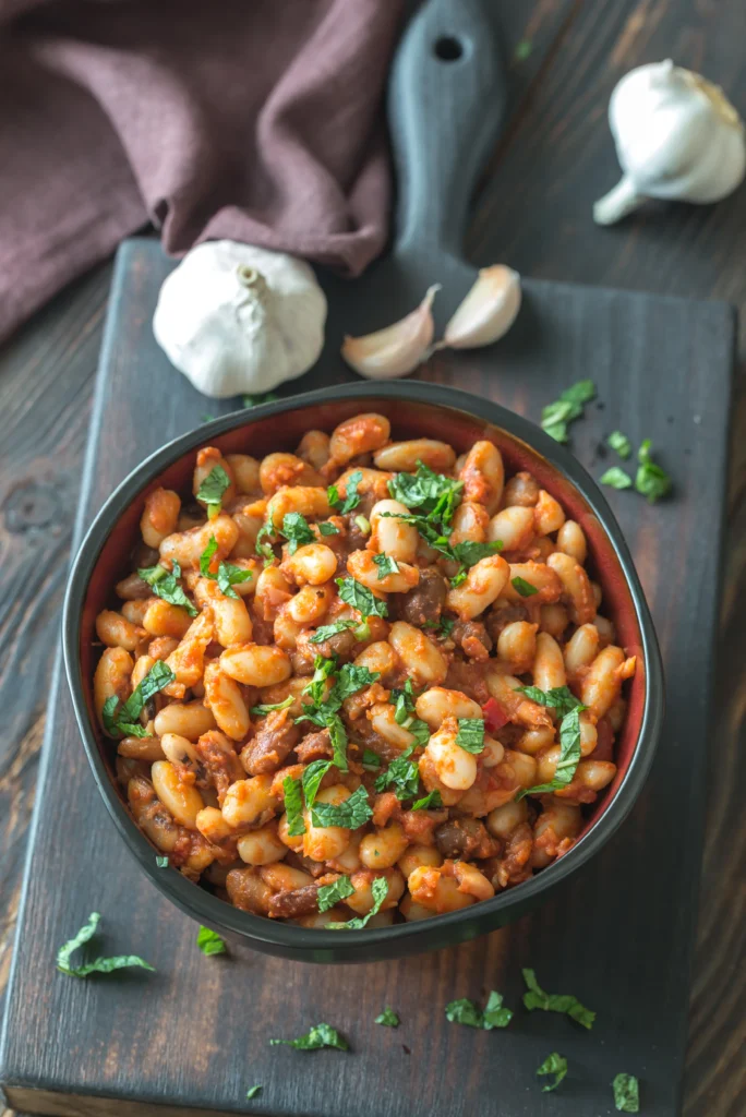 A hearty bowl of lasagna beans topped with melted mozzarella, grated Parmesan, fresh basil, and rich tomato sauce, served with crusty bread.