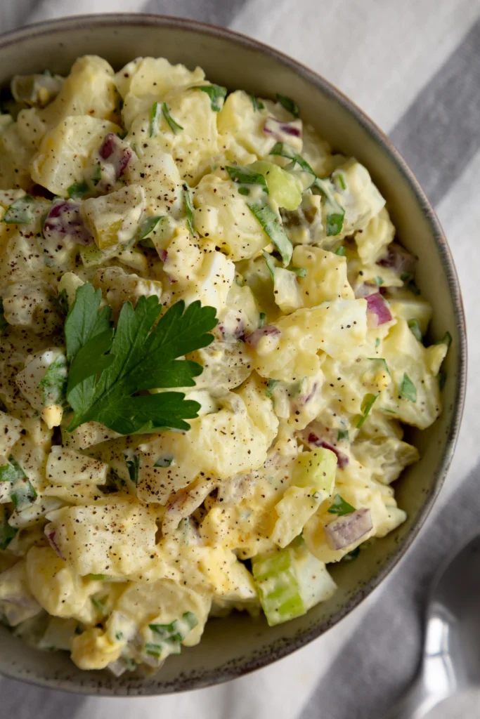 Classic American potato salad recipe with creamy dressing, boiled potatoes, eggs, and fresh vegetables served for BBQ season