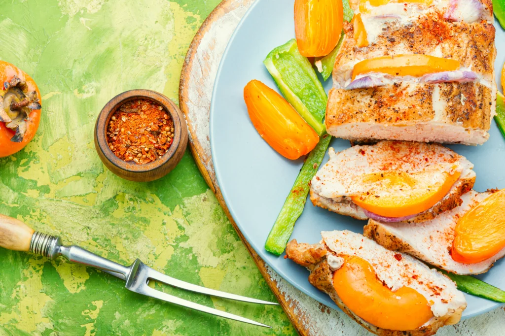Grilled salmon with fresh peach salsa, lime wedges, cilantro, red onion, and jalapeño served on a plate