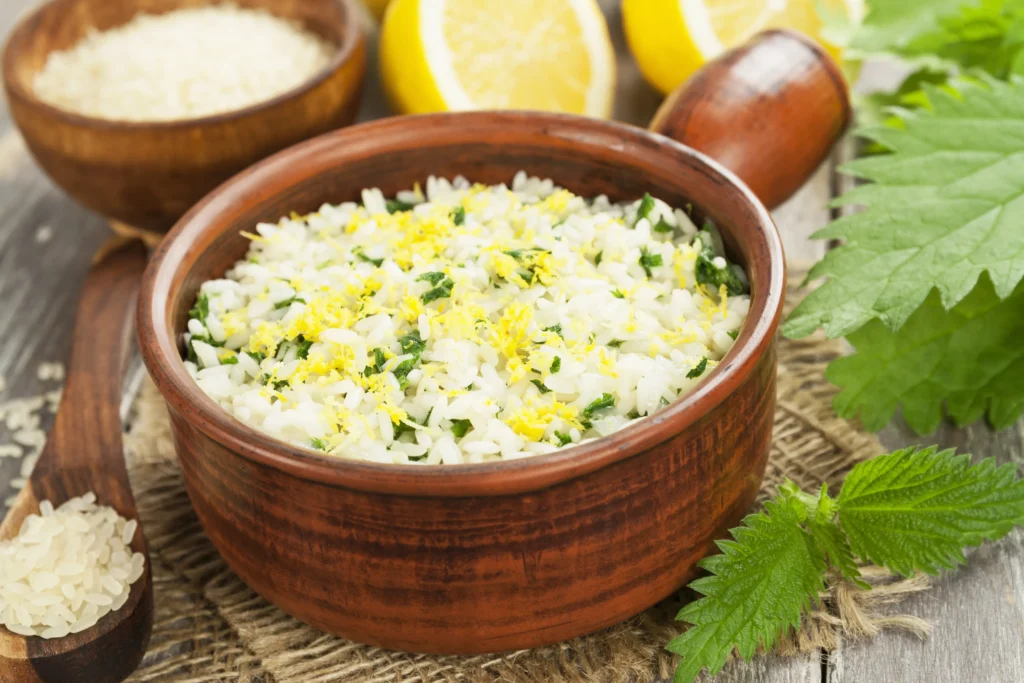Creamy lemony risotto served with fresh Parmesan cheese, lemon zest, herbs, and cracked black pepper in a rustic white bowl.