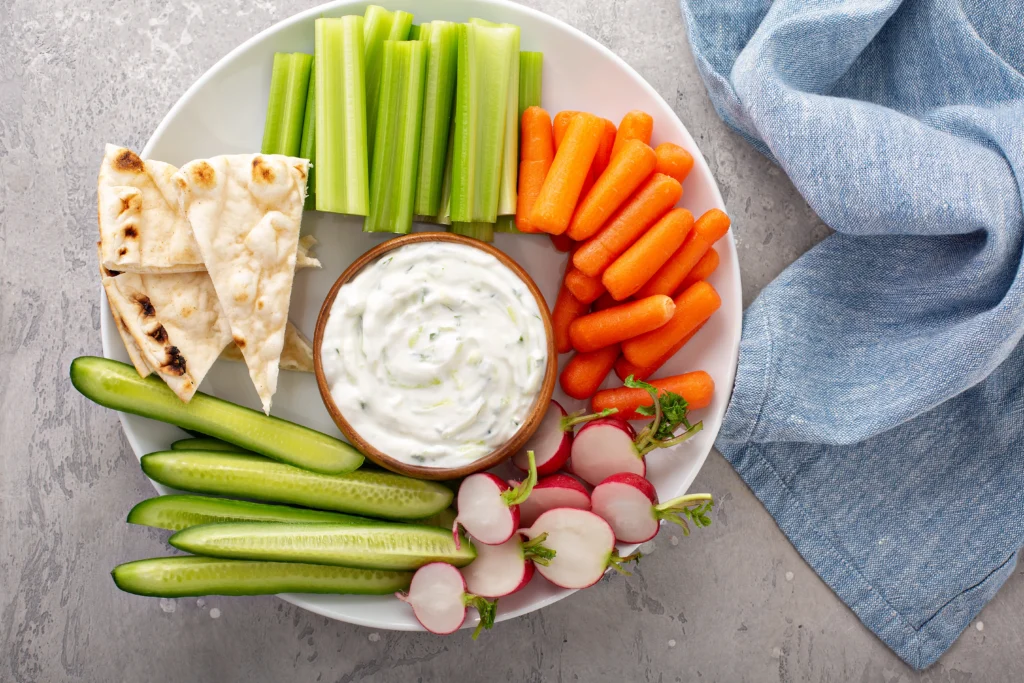 Feta Dip Recipe
A beautifully presented bowl of whipped feta dip garnished with a drizzle of extra virgin olive oil, chopped fresh parsley, oregano, cracked black pepper, and red pepper flakes. The dip is surrounded by warm pita triangles, crunchy crackers, cucumber slices, carrot sticks, and cherry tomatoes on a rustic wooden serving board. This Mediterranean-inspired appetizer is quick to prepare, packed with bold flavors, and ideal for entertaining, holiday gatherings, or healthy snacking.