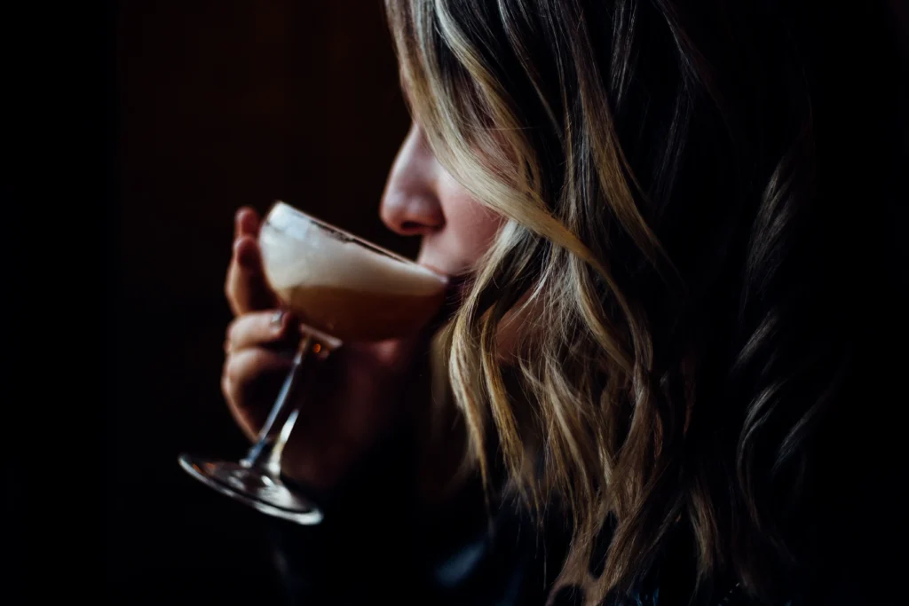Classic Espresso Martini served in a chilled martini glass with a creamy foam topping and three coffee beans, set beside fresh espresso and coffee beans on a dark bar surface.