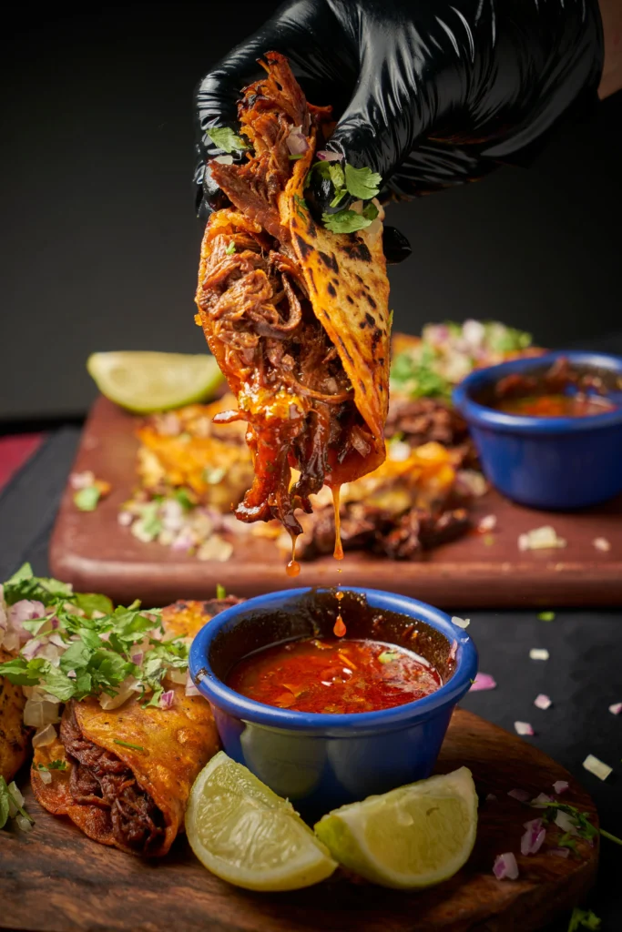 Authentic birria tacos with tender shredded beef, melted cheese, crispy tortillas, and consommé dipping sauce