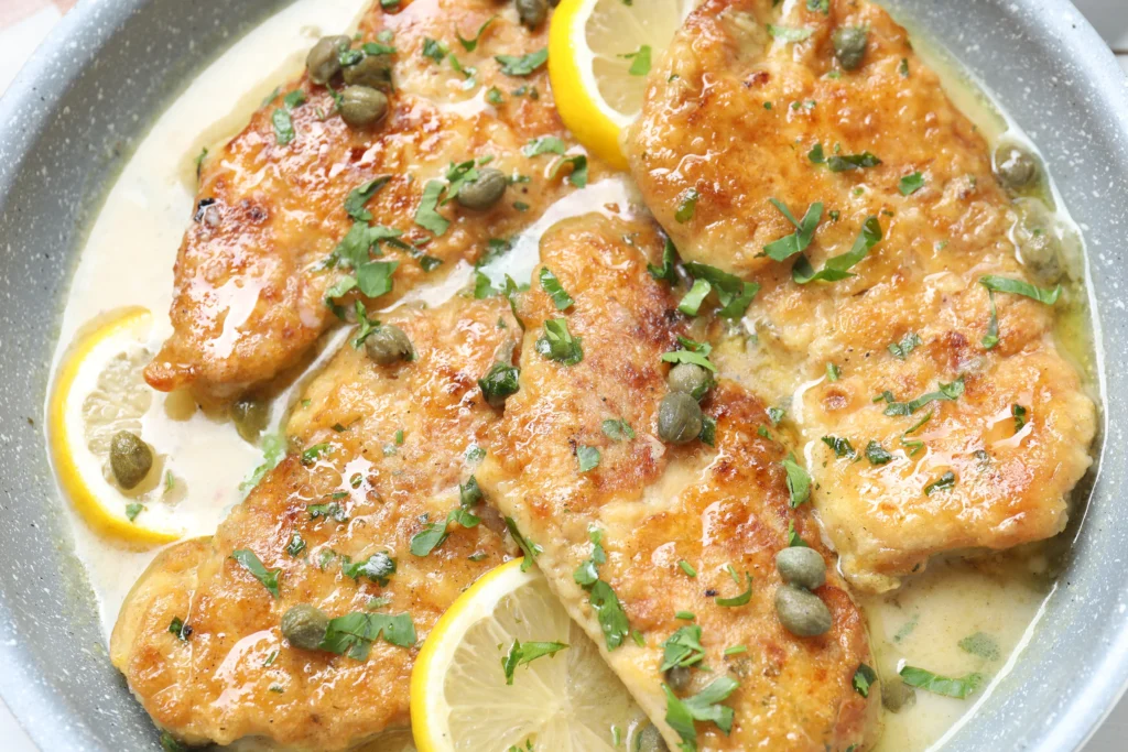 Chicken Piccata Recipe served with a rich lemon caper sauce, fresh parsley, and lemon slices in a skillet, perfect for an easy Italian dinner.