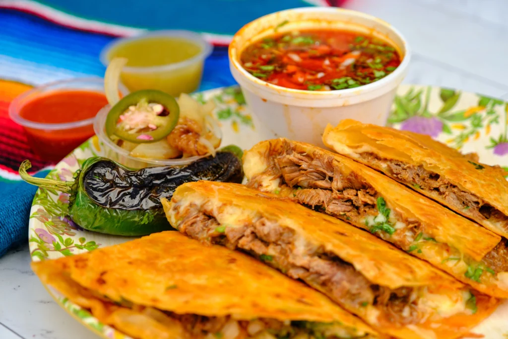 Authentic birria tacos with tender shredded beef, melted cheese, crispy tortillas, and consommé dipping sauce
