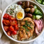 Healthy Greek Chicken Bowls with Tzatziki, fresh vegetables, rice, feta, olives, and grilled chicken