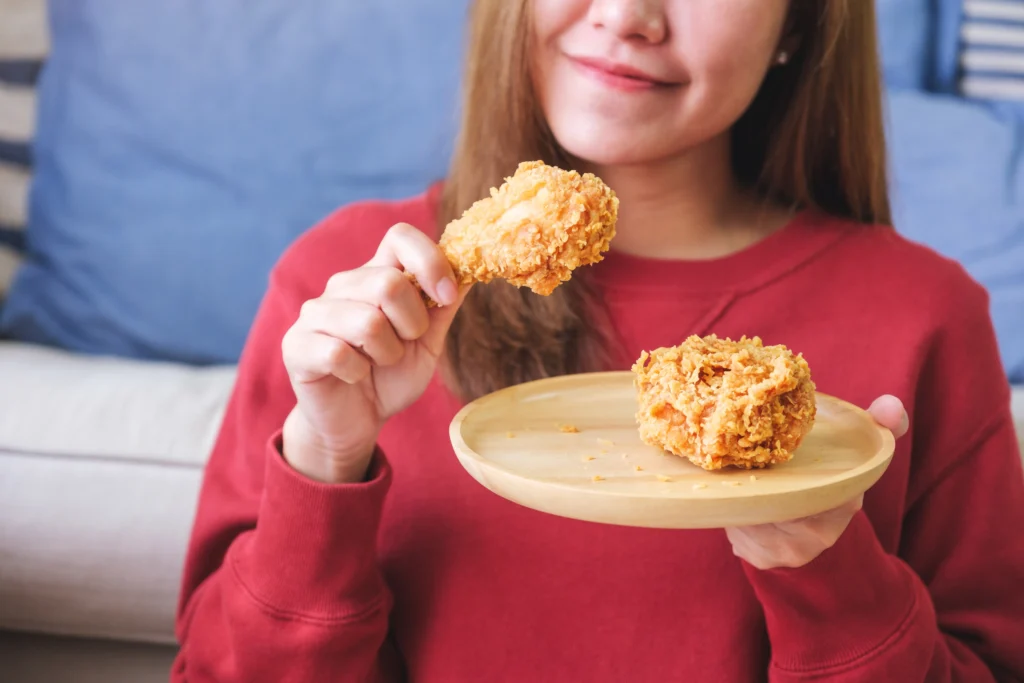 Golden baked cornflake chicken with a crispy golden coating, served on a plate with mashed potatoes, fresh green beans, and a sprinkle of parsley.