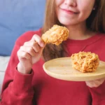 Golden baked cornflake chicken with a crispy golden coating, served on a plate with mashed potatoes, fresh green beans, and a sprinkle of parsley.