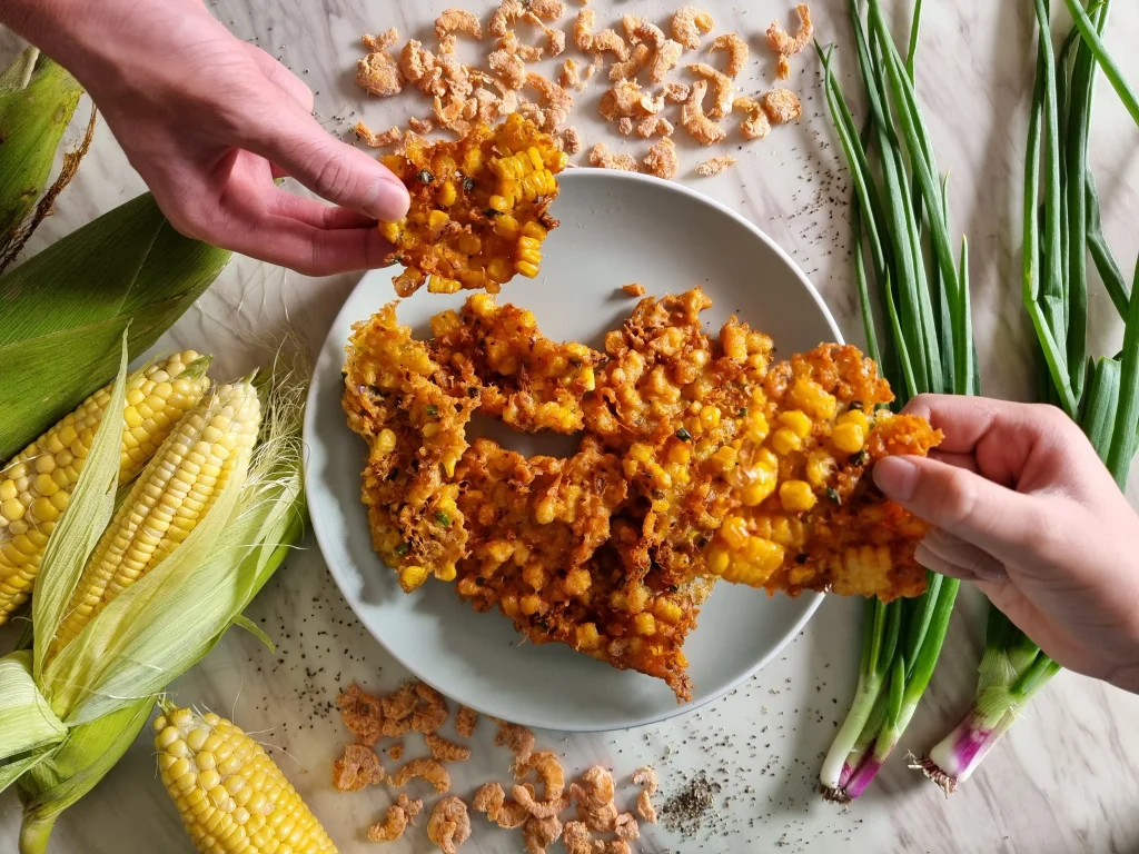 Golden crispy corn fritters drizzled with spicy hot honey, served as a sweet and savory appetizer.