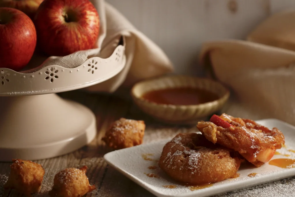 Glazed apple pie fritters topped with sweet vanilla glaze, homemade fall dessert with cinnamon and fresh apples